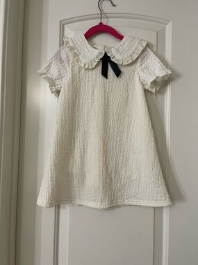 🎀 Girls' Cream Textured Peter Pan Dress with Black Bow